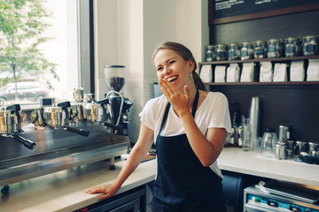 Young Caucasian barista smiling laughing at work place. Small business concept