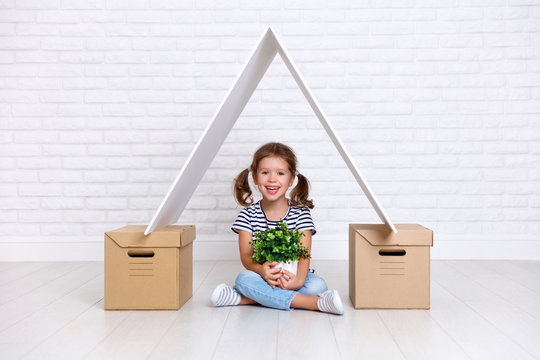 Concept of moving and housing. happy child girl with boxes