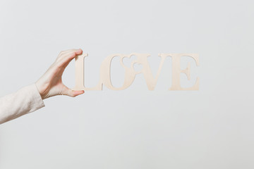 Obraz na płótnie Canvas Close up woman holding wooden light word Love in hand isolated on white background. Copy space for advertisement. With place for text. St. Valentine's Day or International Women's Day concept.