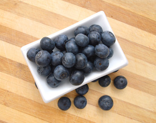 composition from a fresh bow blueberry in plate on wooden board