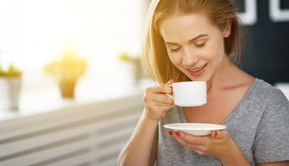happy young woman with cup of morning coffee in bed