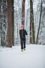 Naklejka na ściany i meble Photo of running athlete among trees in winter forest