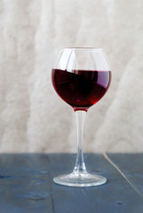 A glass of red wine on a wooden table on a light background