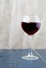 A glass of red wine on a wooden table on a light background