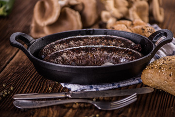 blood sausage in black cast iron baking pot on wooden table 