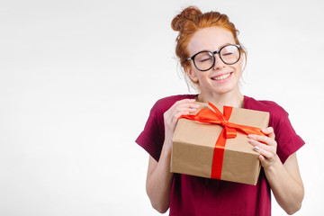 Fototapeta premium Happy dream pretty young redhead woman in glasses holding gift box on white background