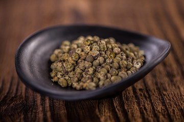 detail close up whole peppercorn in black dish on wood table