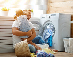 Happy family man father householder and child   in laundry with washing machine