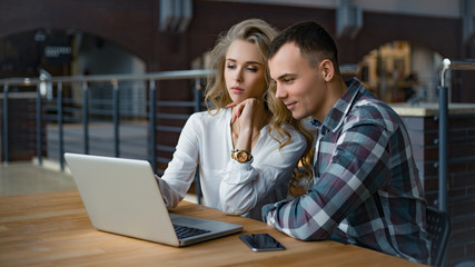 A couple is looking for the information in the internet. They are talking and smiling.