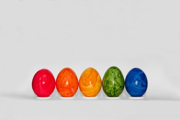 fünf Ostereier in Regenbogenfarben om eomer Reihe vor weißem Hintergrund