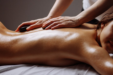 woman getting hot stone massage in spa salon. Beauty treatment concept.