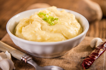 mash potatos in a white porcelain bowl on wood table 