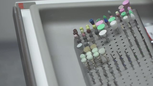 Close-Up Of Dentist's hand in gloves selecting a bur from set in a shelf .Dentist Equipment - Dental Care