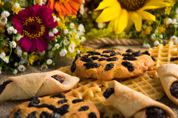 delicious cookies and waffles on a table on a background of flowers