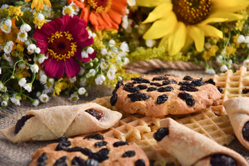 delicious cookies and waffles on a table on a background of flowers