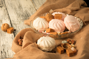 still life of sweets, marshmallows and candies in a glass vase on a wooden table