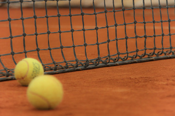 Tennis balls on red court with gray net