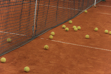 Tennis balls on red court with gray net