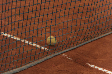 Tennis balls on red court with gray net