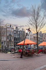Architecture of Amsterdam. City buildings. Stone pavement in the old town. Bright sunset....
