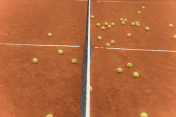 Tennis balls on red court with gray net