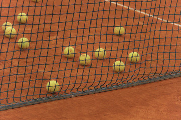 Tennis balls on red court with gray net