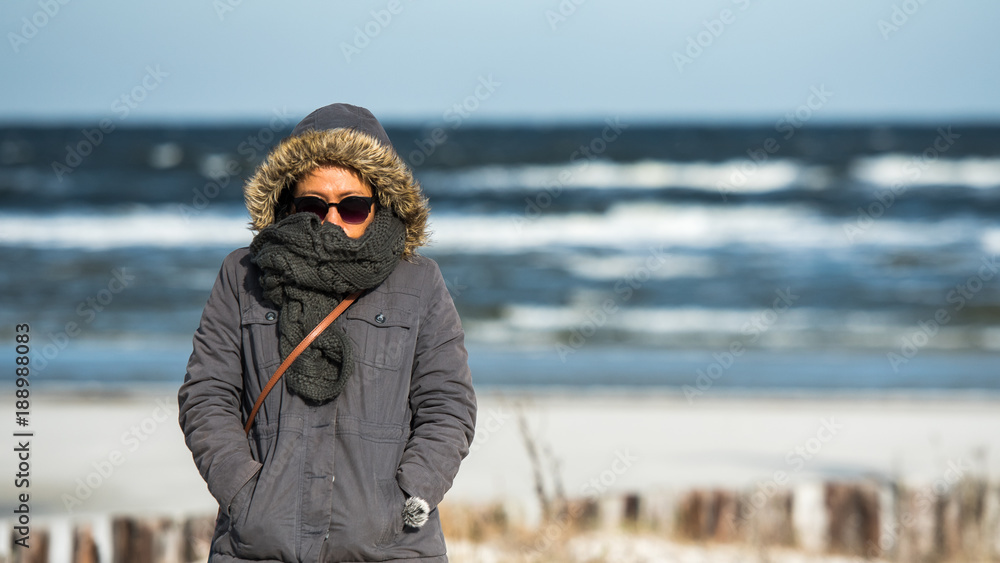 Wall mural Woman standing at Ocean in Freezing weather