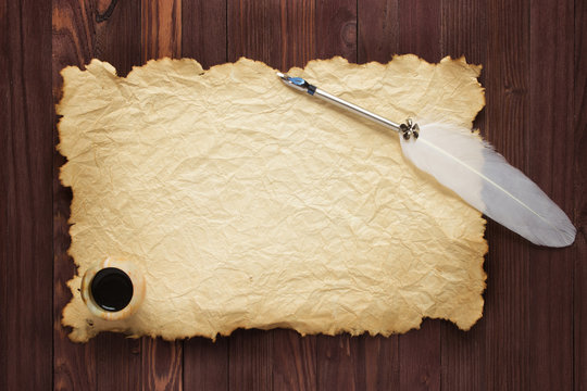 old paper and inkstand with quill pen on a wood background