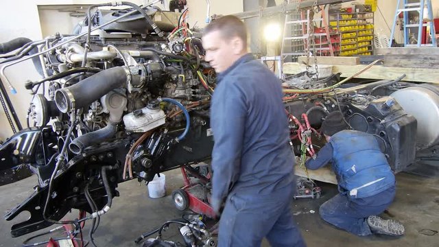 Mechanics working on diesel semi truck engines in garage for repair