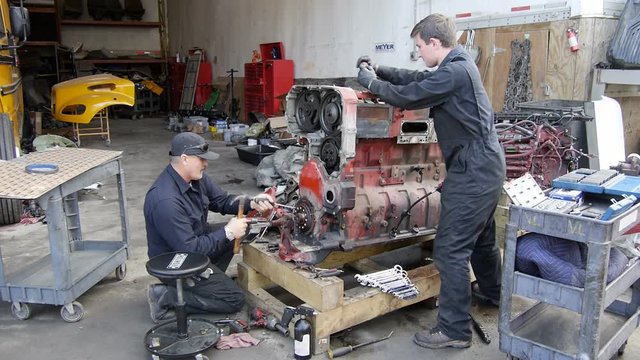 Mechanics working on semi truck engine in repair shop garage