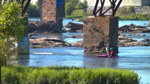 Kayaking On The James River In Richmond VA With People Navigating Between Concrete Bridge Supports And Rocks In The Virginia State Capital City On A Sunny Day