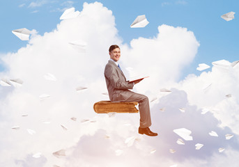 Businessman or student reading book and paper planes flying around