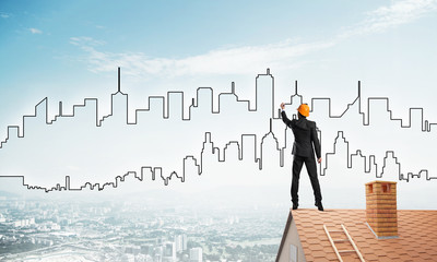 Man architect draw silhouette of modern city on blue sky. Mixed media
