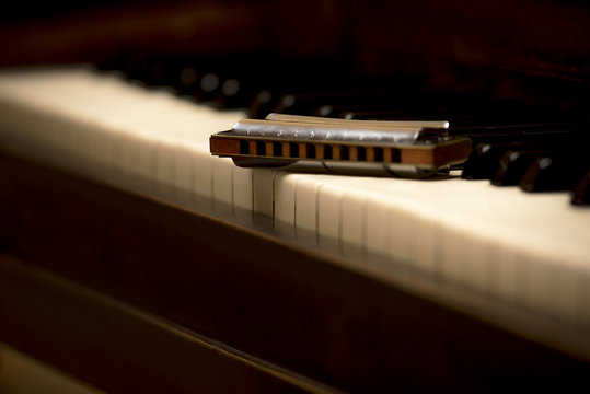 Close up macro photo of chromatic wooden harmonica on white piano keys, shallow focus