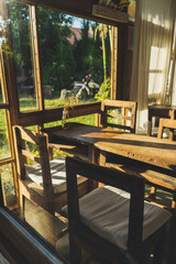 Wooden table and chairs put beside the windows with afternoon light.