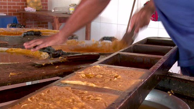 A man scoops caramelized sugar into block moulds