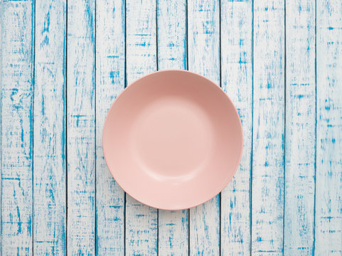 A Pink Plate On An Old Wooden Table