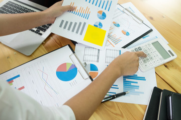 business men working on wooden desk(table) with notebook computer paper, pencil and hand in office, financial concept.