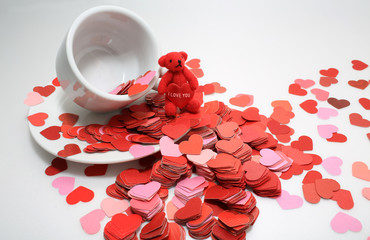 cup of tea ,full of heart with i love you words on the spread of small heart, white and red background