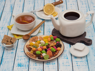 Cup of tea with lemon, a teapot and dried fruits on a wooden table