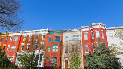 Colorful townhouses before sunset in spring, Washington DC, USA. Historic brick townhouses in Shaw neighborhood on a quiet street with trees.