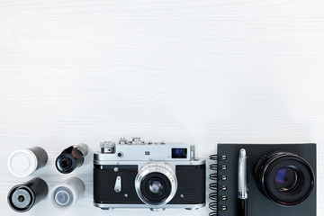 old classic photo camera, negative film rolls, notebook and fountain pen on white background, flat...