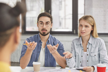 Indoor shot of professional financiers use paper documents, discuss something actively, talk about monthly report or share ideas for making, conclude agreement, demonstrate combined efforts for work