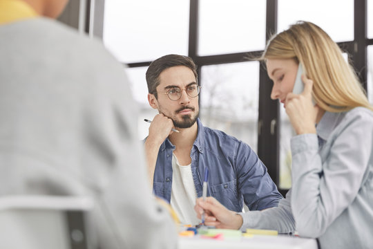 Back view of successful young people collaborate for common aims, discuss something, sit at working table. Blonde busy female has telephone conversation, tries to check or varify her balance.