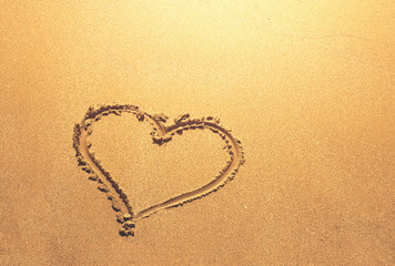 heart symbol written on sandy beach