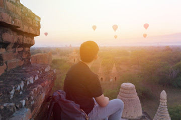 Silhouette of young male backpacker sitting and watching hot air balloon travel destinations in...
