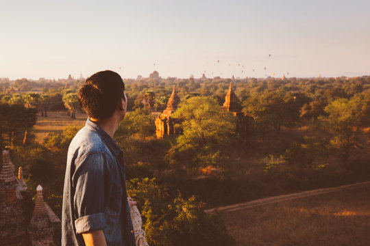 Silhouette of young male backpacker watching sunset and pagoda in Bagan, Burma.