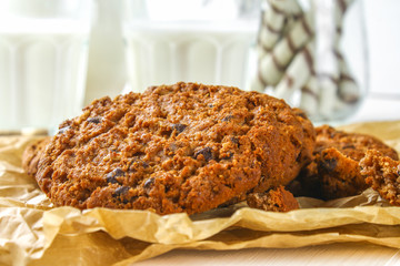 Homemade oatmeal cookies. A parchment paper on the background. Milk on a wooden white table.