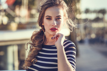 Fototapeta premium Blonde woman, model of fashion, sitting in urban background.