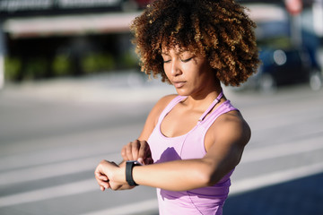 Fototapeta na wymiar Young black woman using smartwatch touching touchscreen
